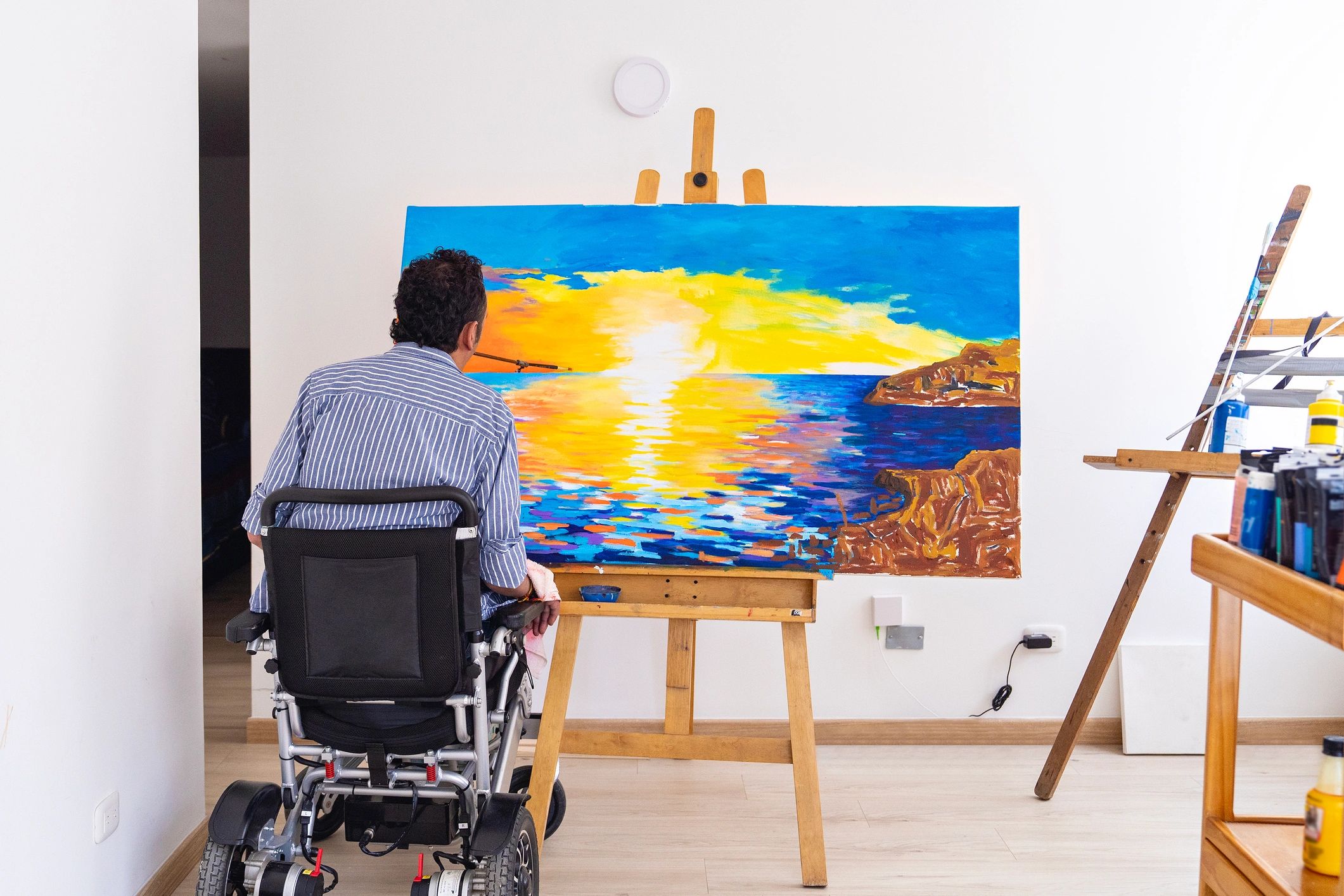 Artist painting a sunset seascape in a home studio